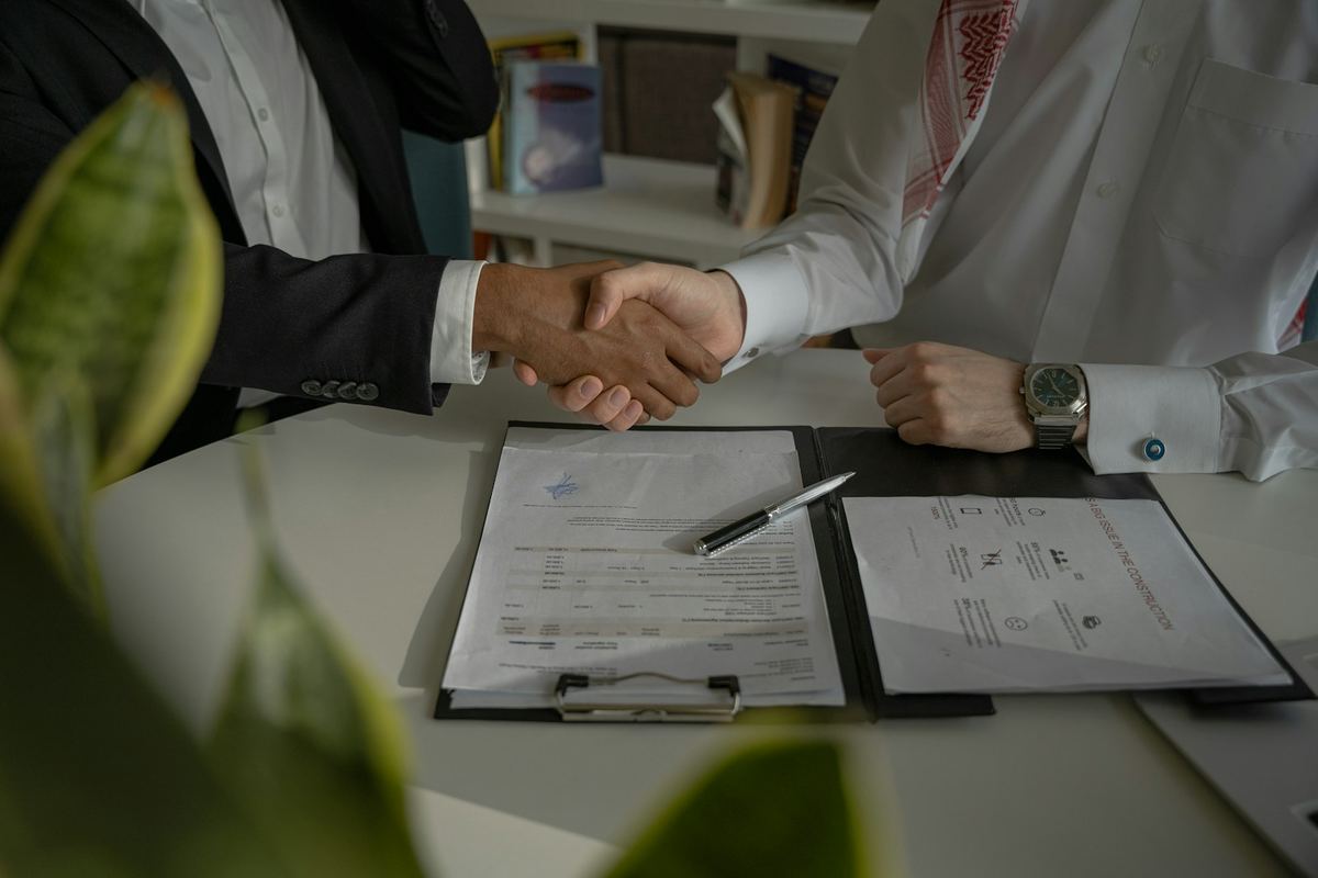 Two people shaking hands over a signed agreement