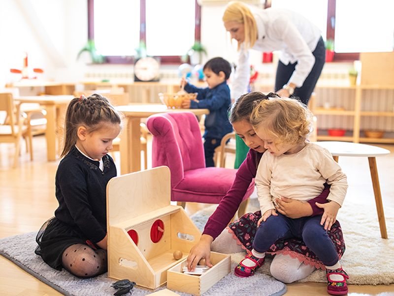 Children playing with an educator in a bright daycare classroom
