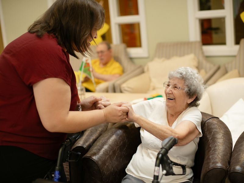 A caregiver holding hands with a smiling senior resident